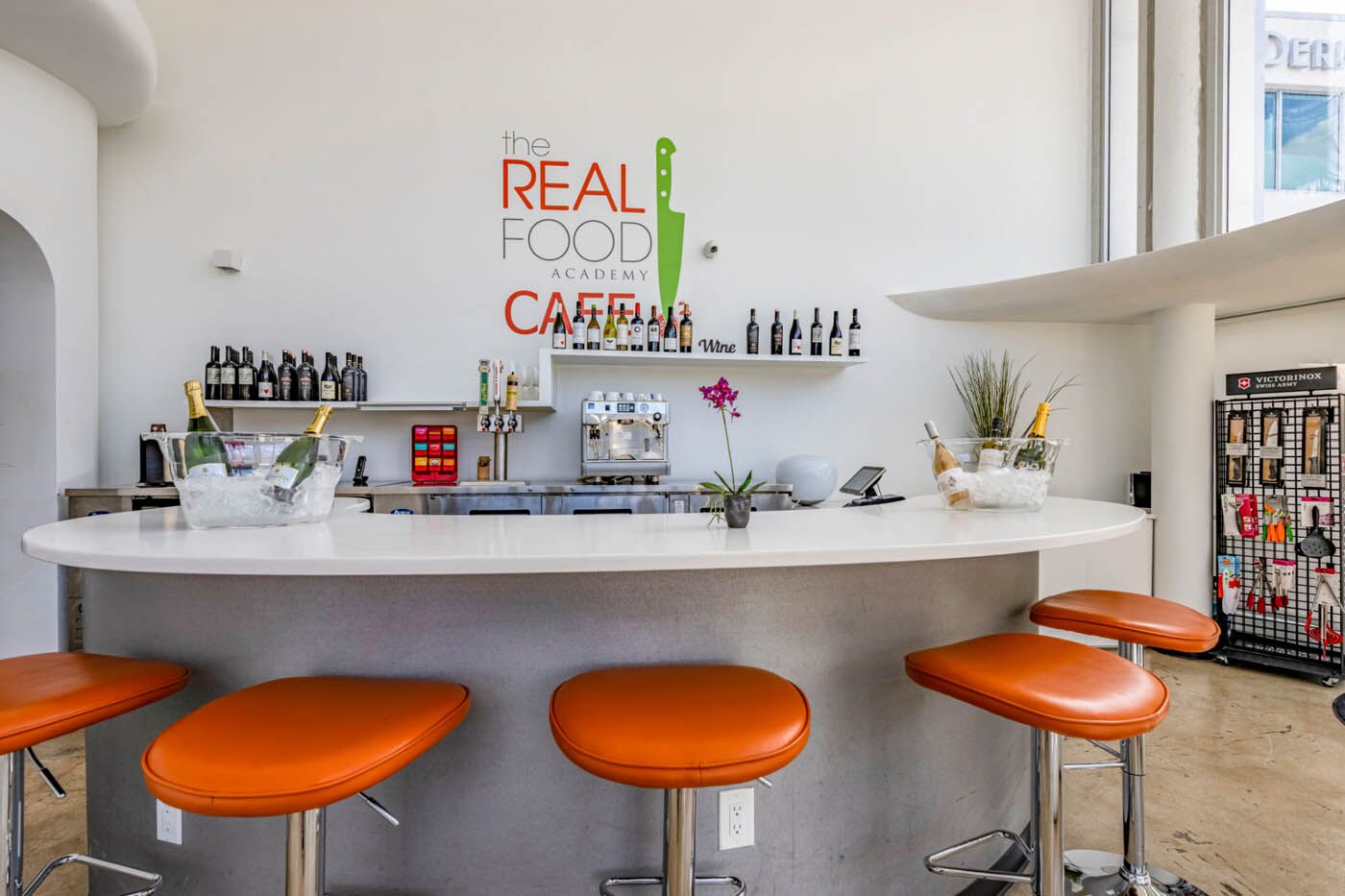 The Real Food Academy Miami bar with orange chairs.