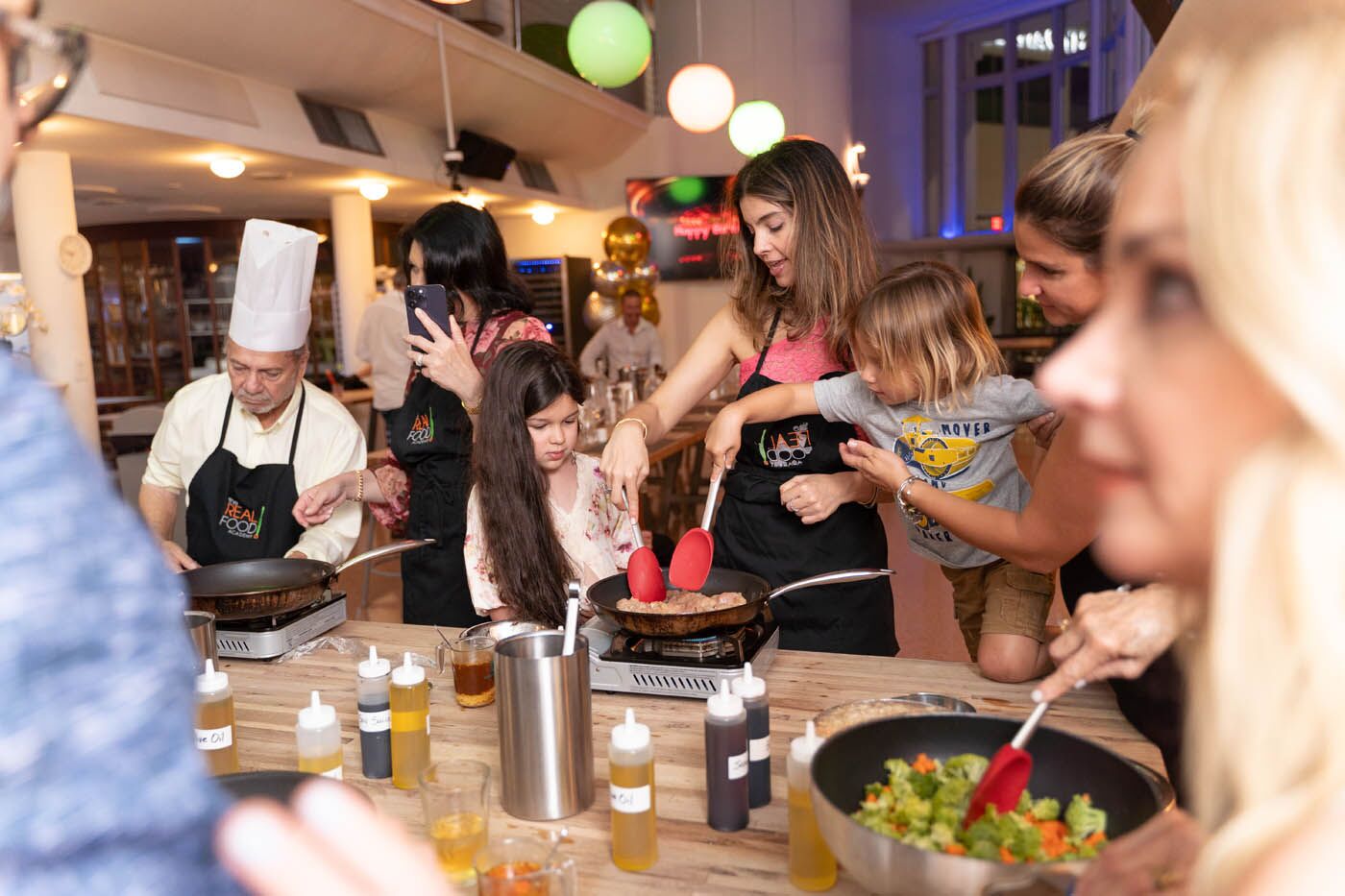 A mom with her kids participating at The Real Food Academy Orlando's chef class.