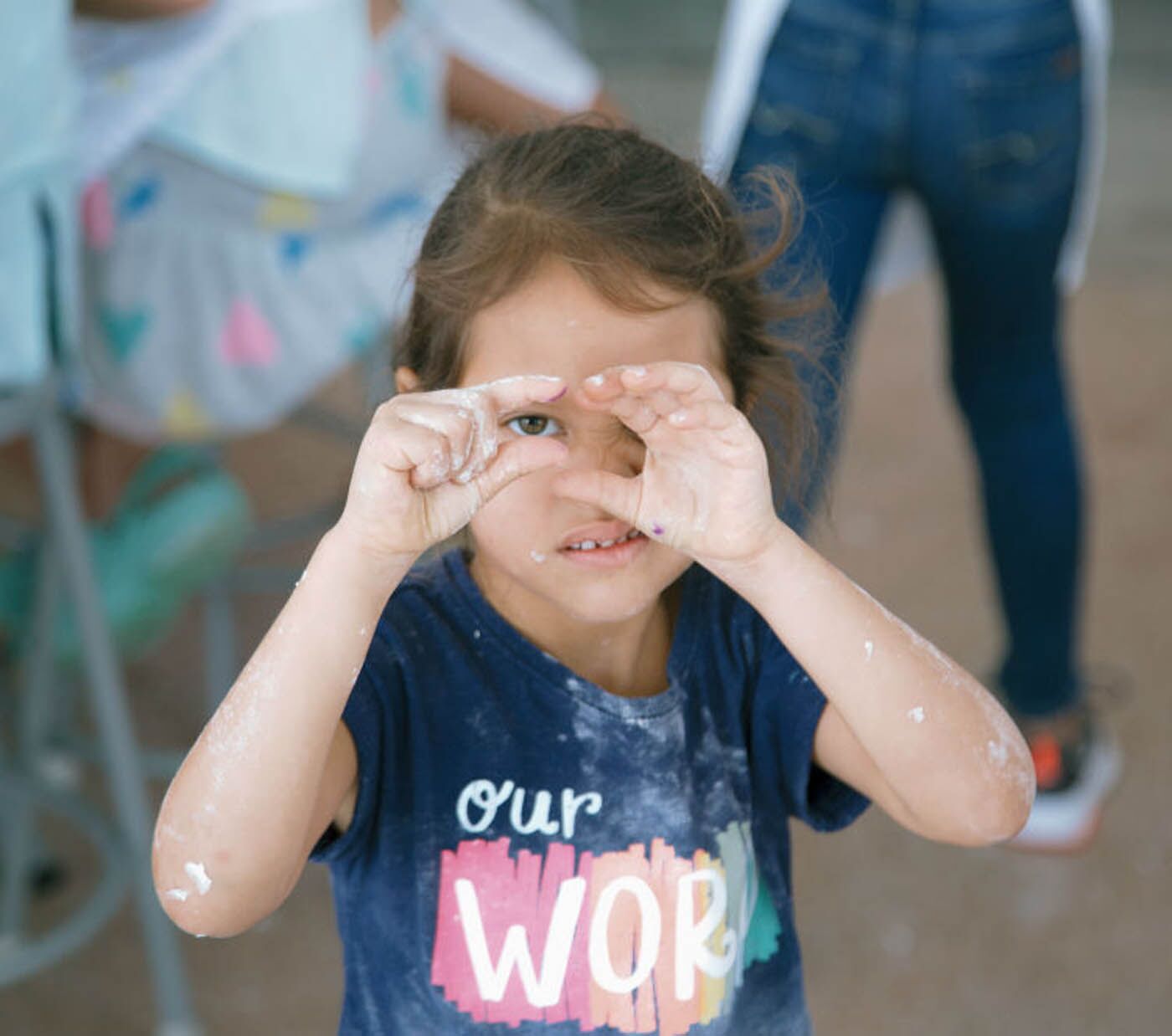A young girl covered in flower, but having a great time at The Real Food Academy Miami's kids cooking camp.