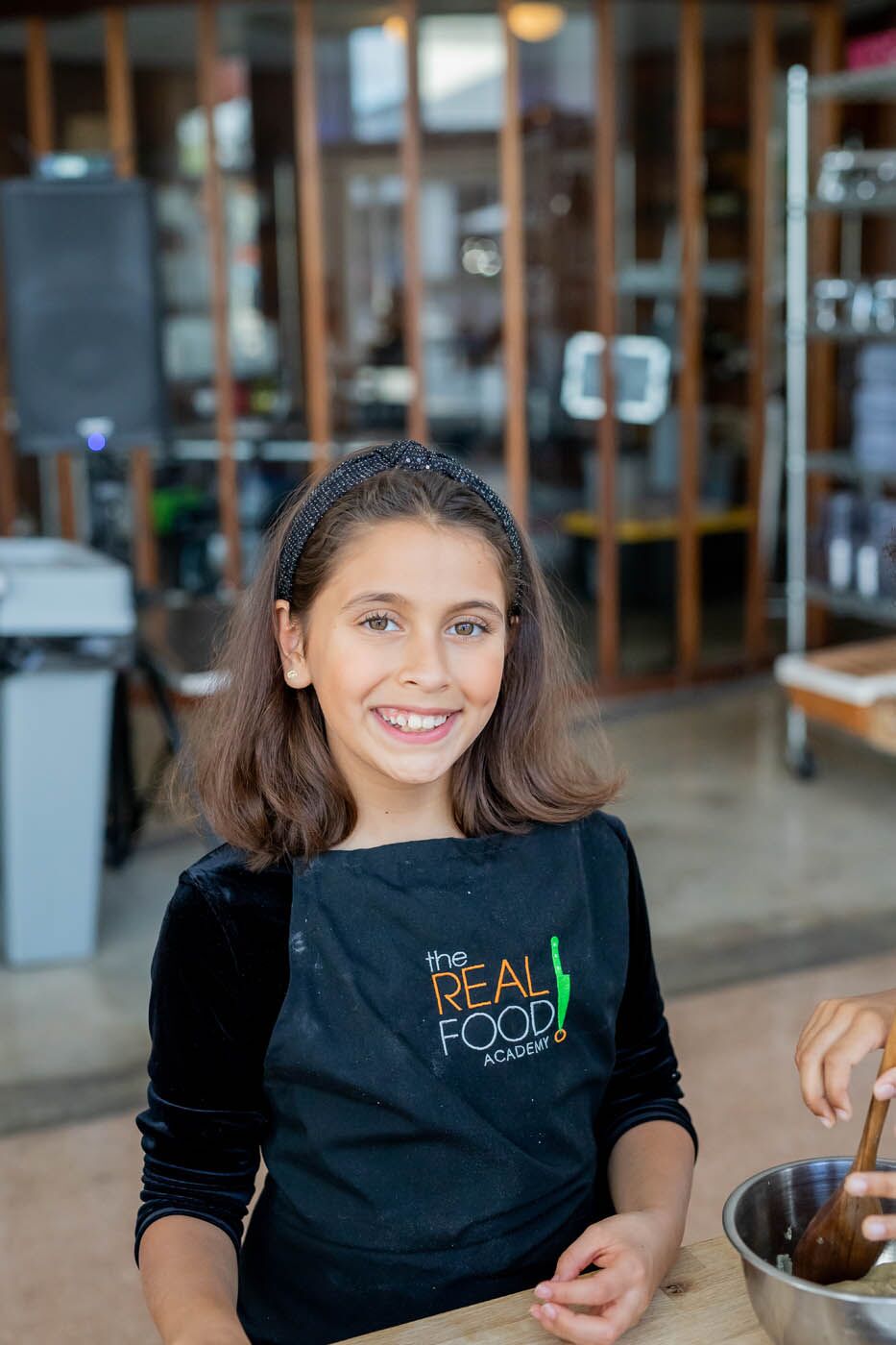 A younger girl at a kids cooking camp with The Real Food Academy Miami - a perfect place to meet friends!