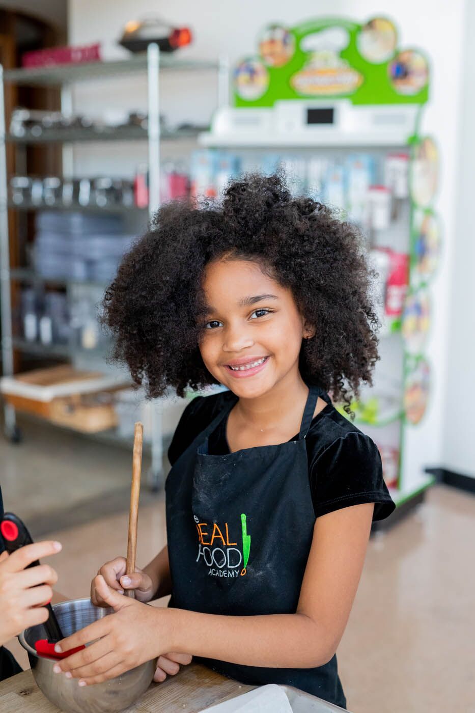 A young girl getting her hands in the mix at The Real Food Academy's cooking summer camp in Miami, FL.