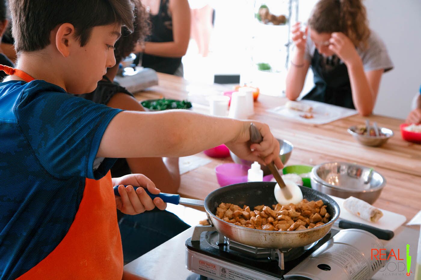 A young boy making stir fry at The Real Food Academy Orlando's cooking classes for kids.