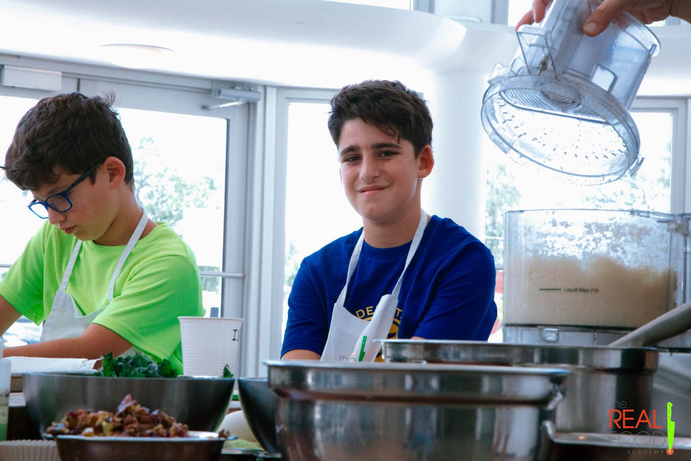 A young boy smiling in front of mixing bowls, check out our cooking classes for teens in Miami, FL.