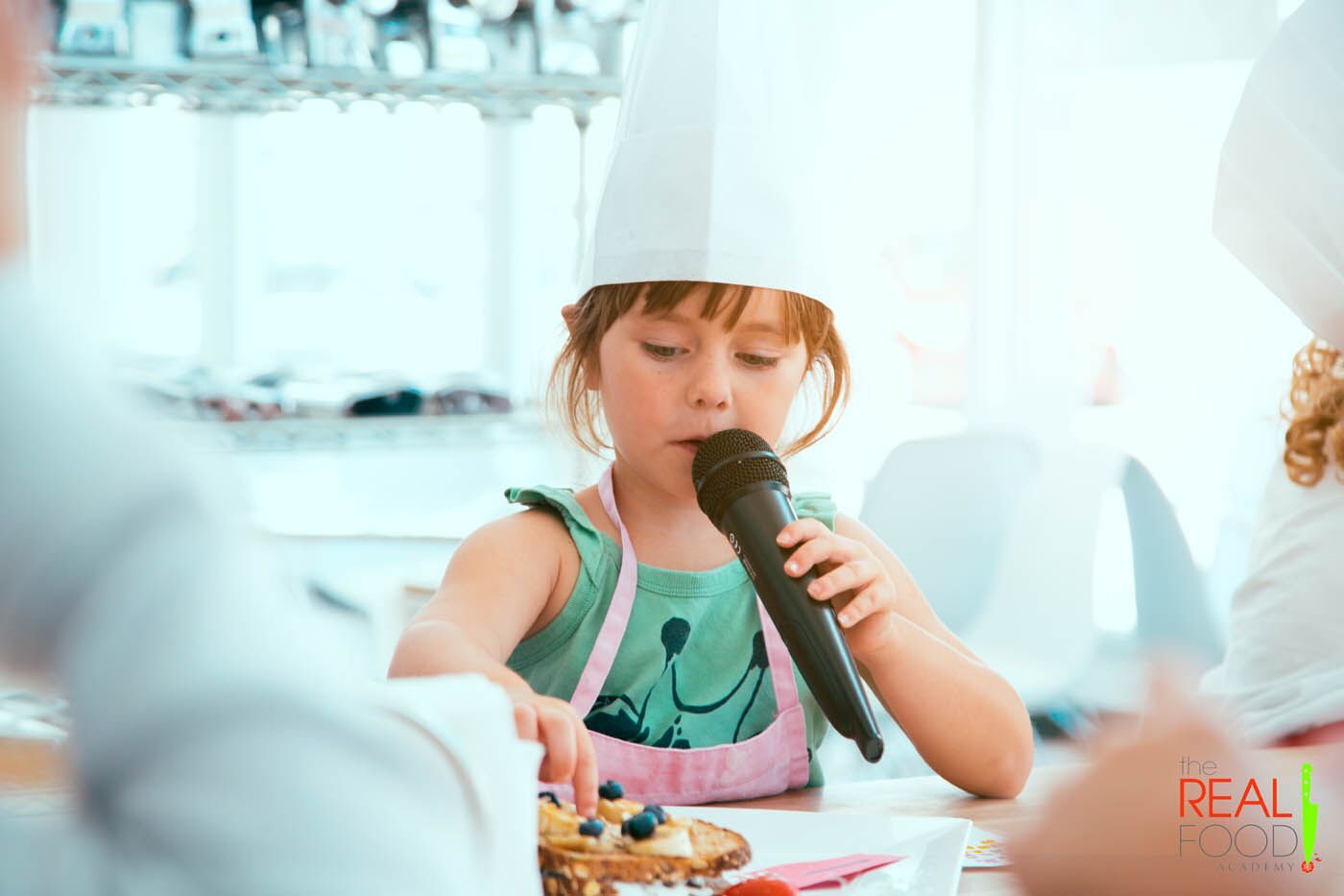 A young girl with a microphone at The Real Food Academy Miami's kids cooking camp.