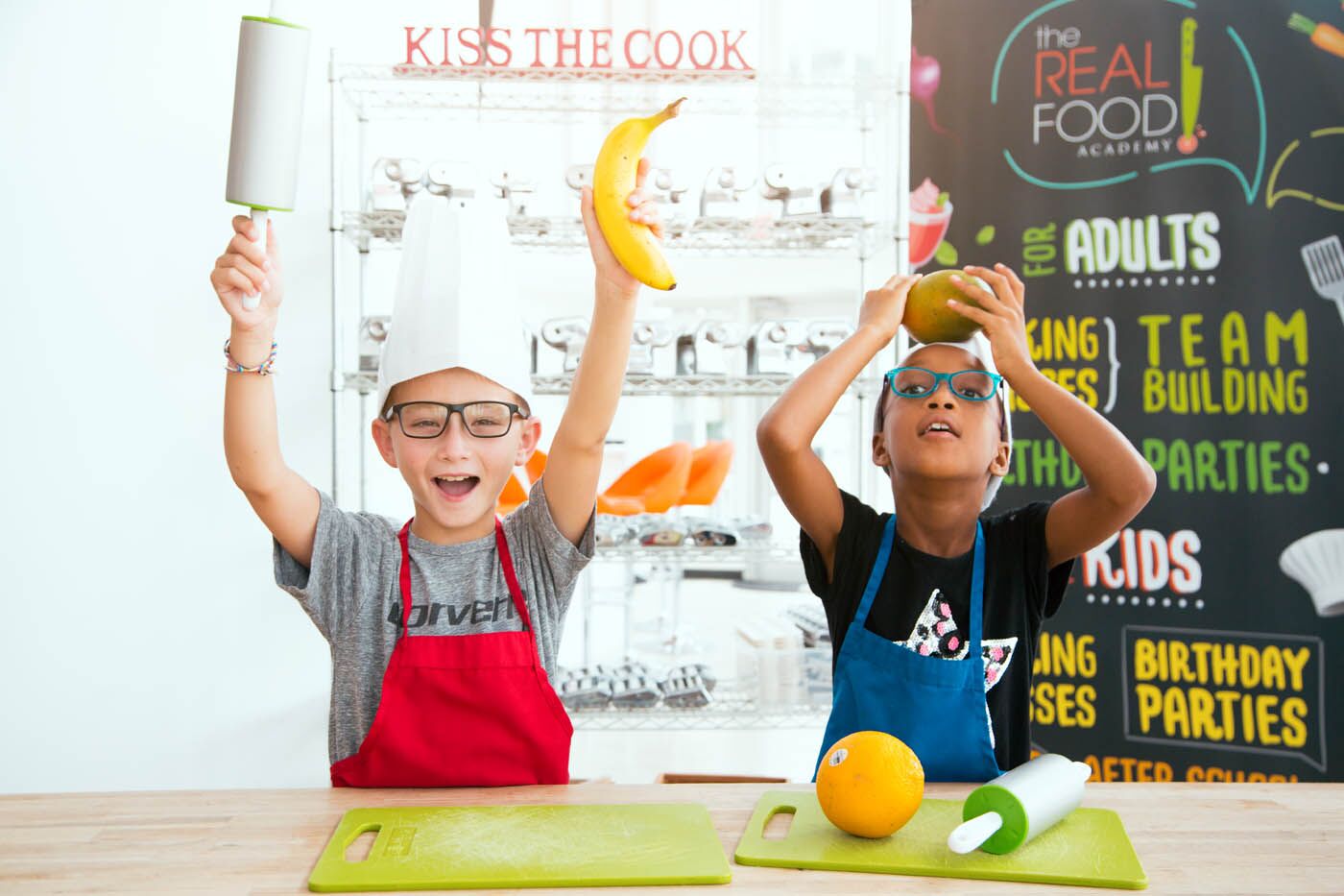 Two little boys playing with fruit at The Real Food Academy's day cooking camps in Orlando, FL.
