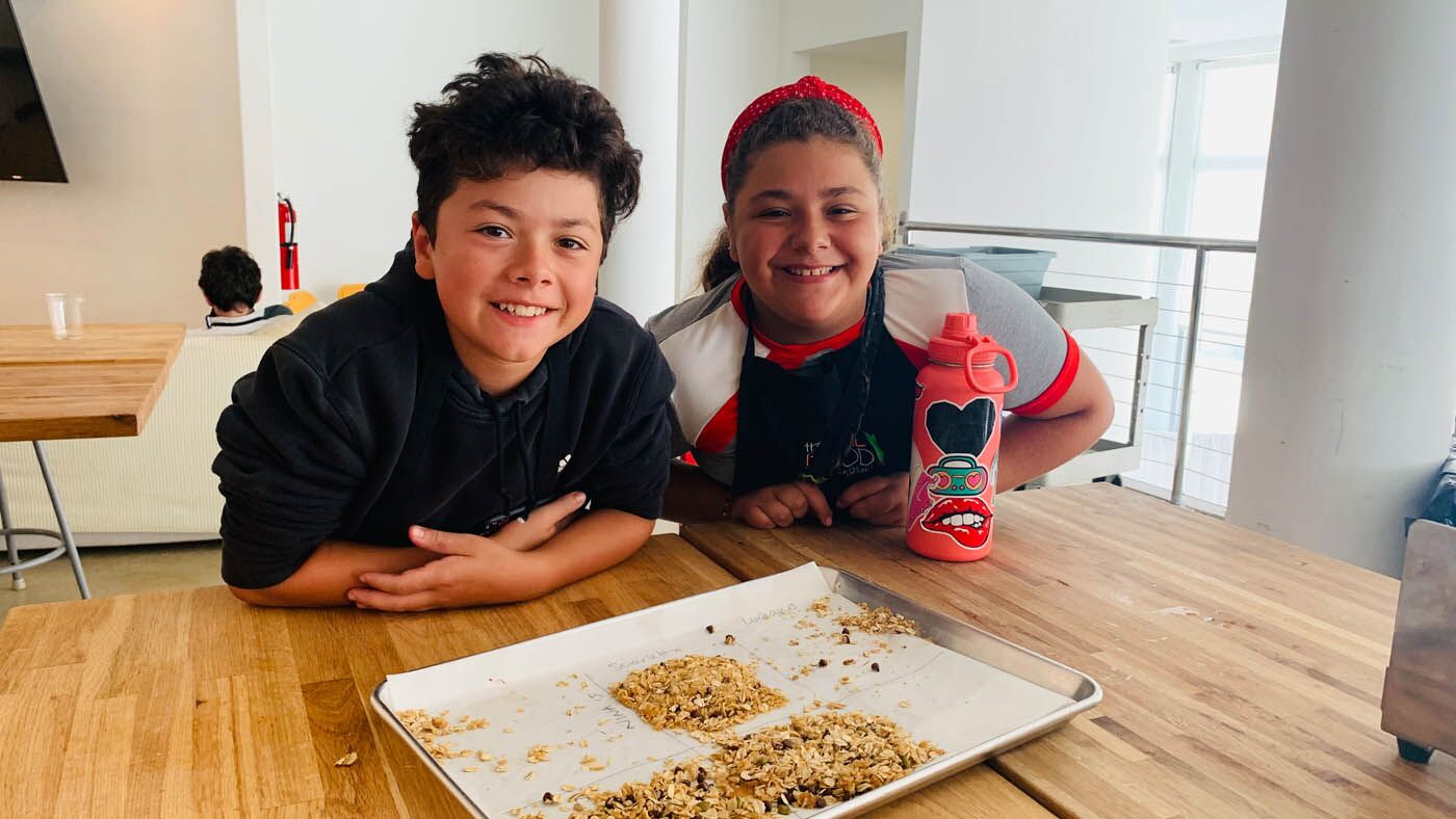 Two children posing with homemade granola from a The Real Food Academy Miami cooking camp.