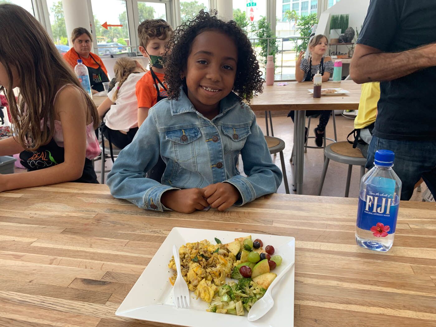 A little girl at The Real Food Academy Orlando's after school program with a fresh plate of fruits and veggies.