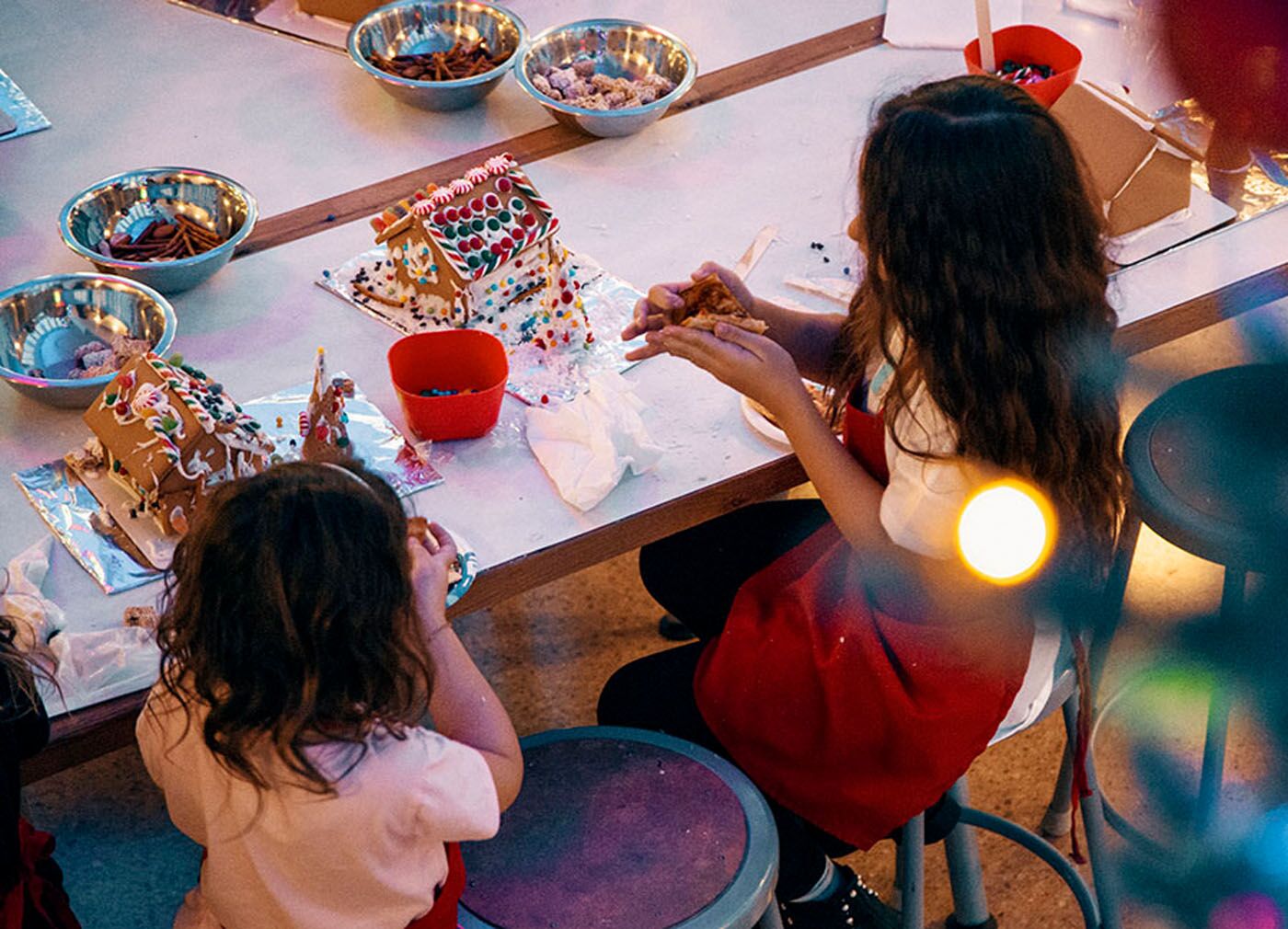 An image of two young girls decorating at The Real Food Academy's gingerbread house class.