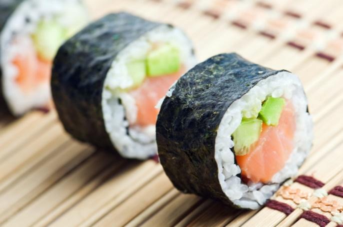 A picture of a The Real Food Academy prepared salmon roll with seaweed on the outside.