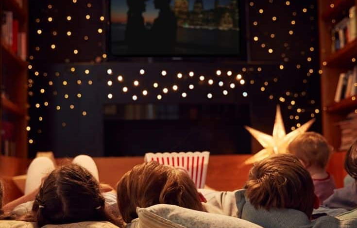 Image of kids laid in front of TV with a movie queued up