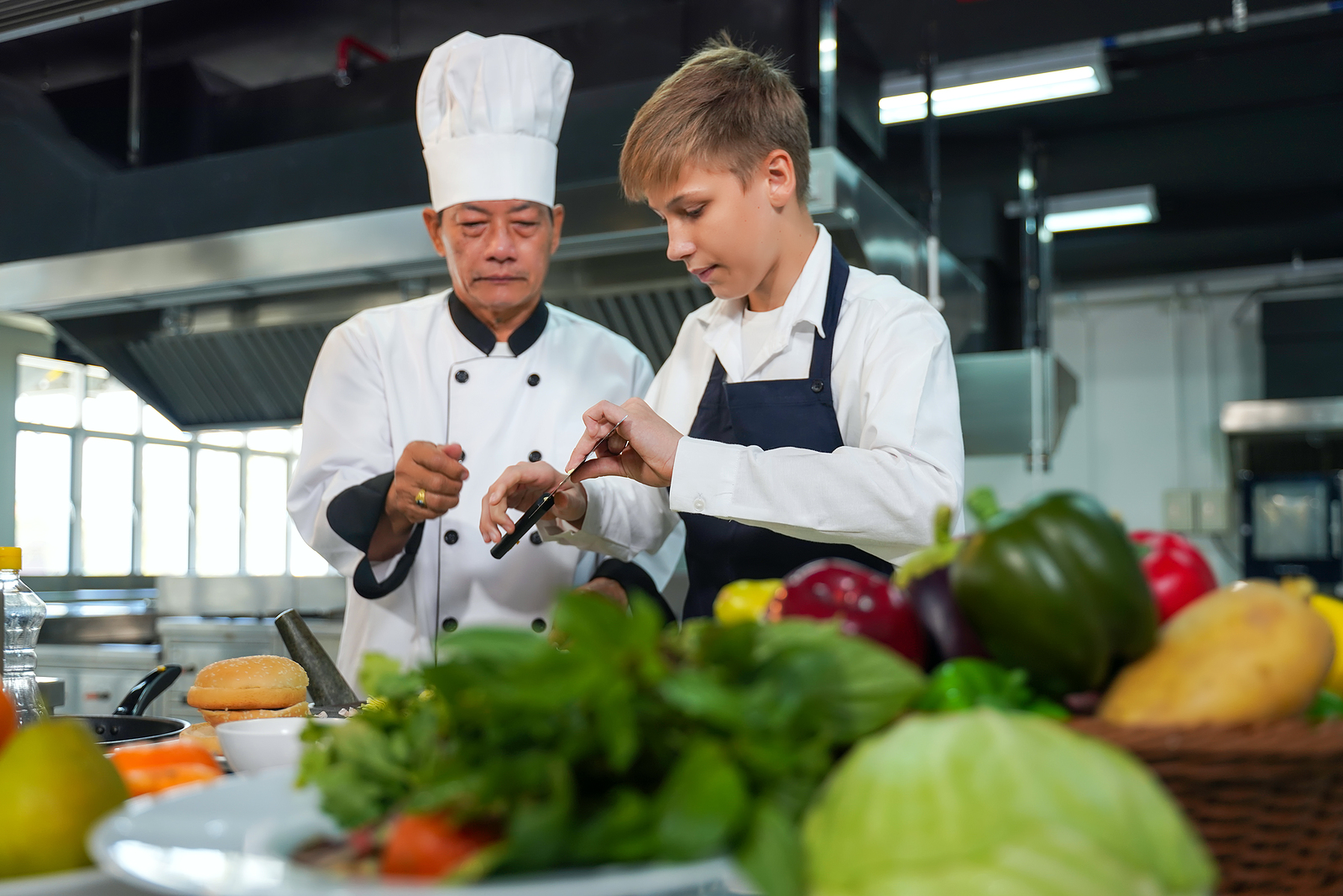 A chef from The Real Food Academy teaching a young boy in a cooking class.