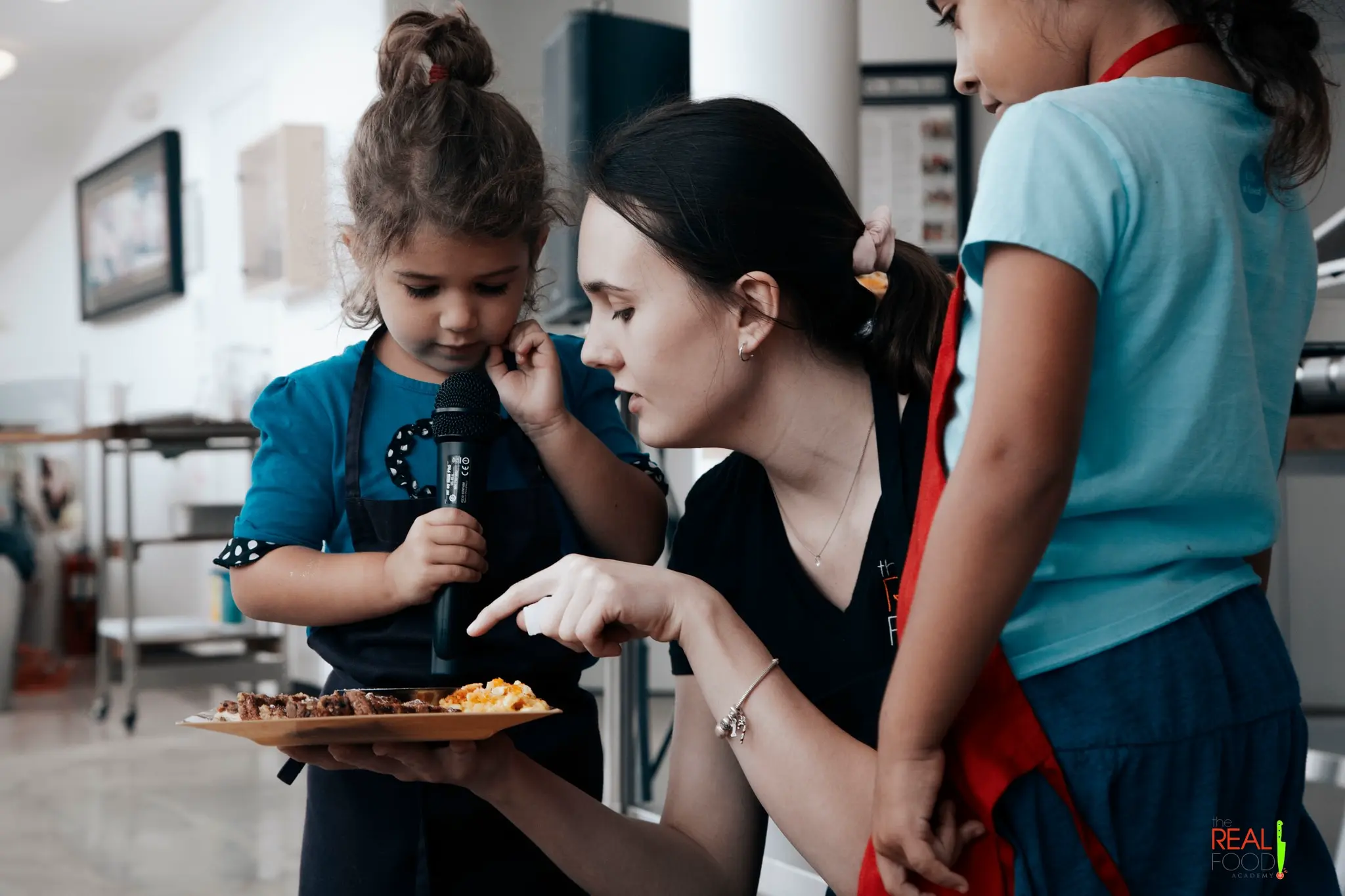 A Real Food Academy cook teaching a young child at one of our growing kids' cooking classes.