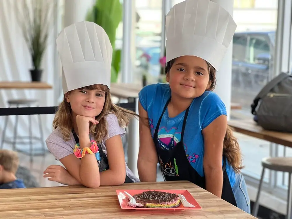 Two girls having fun and learning healthy recipes at a Real Food Academy kid's cooking class.