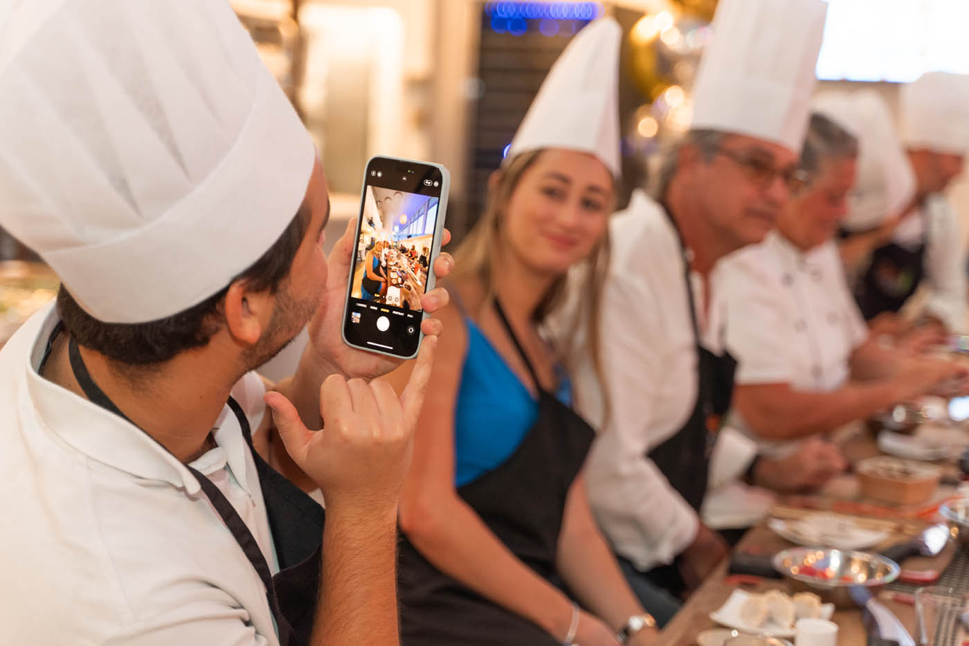 A man taking a picture of his corporate team at The Real Food Academy Miami's team building cooking class in Miami, FL.