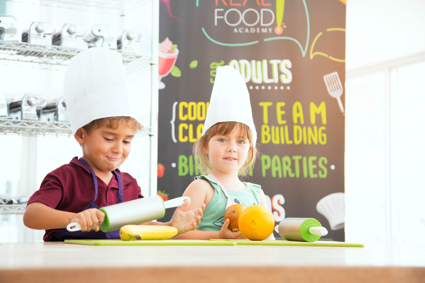 Two little boys in chefs hat participating in The Real Food Academy's cooking summer camp in Miami, FL. 