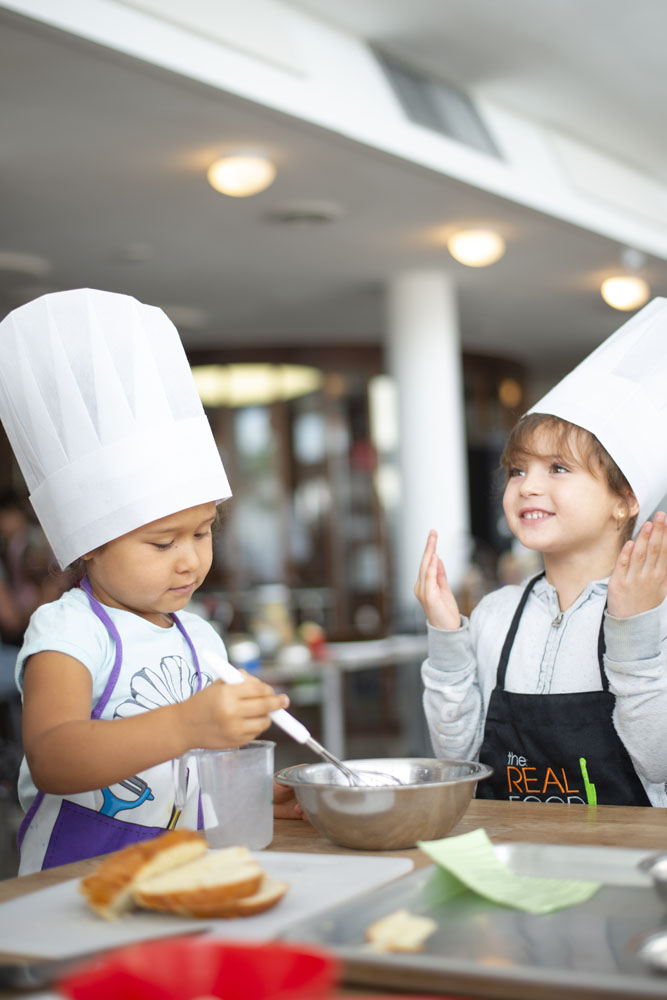 Two young children cooking together at The Real Food Academy Miami.