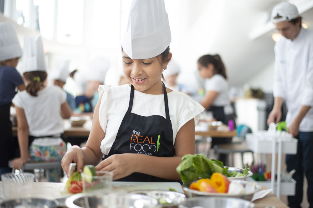 An image of a young girl cooking at The Real Food Academy's weekend and afterschool programs - kids activities in Miami, FL. 