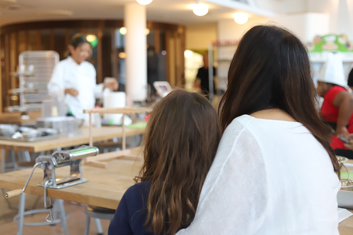 The back of a mom and daughters head watching chef marie teach our mommy and me classes in Miami, FL.